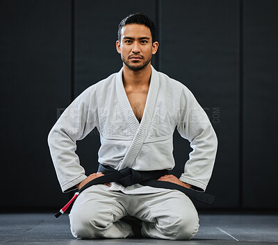 Buy stock photo Male coach ready for karate training at fitness studio, looking serious at dojo practice in gym and sitting on the floor at a self defense class. Portrait of tough, healthy and active trainer