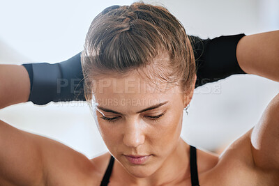 Buy stock photo Face of a young female boxer getting ready to train in the gym for a boxing match. Sporty, active and healthy athlete tying her hair to exercise. Motivated woman doing a fitness workout.