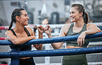 Happy and smiling women bumping fists after being active, exercising and training in a ring. Team of female boxers, fighters or sports athletes standing together in a gym, fitness center or club