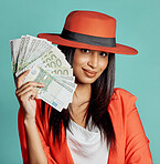 Trendy, stylish and elegant rich young woman holding cash money after successful competition winnings. Smiling fashionable female standing against blue studio background with banknotes  