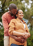 Romantic, loving and caring husband hugging his wife from the back in nature while on a date. Young, African and happy couple embracing each other while spending quality time together outdoors.