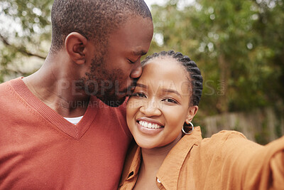 Buy stock photo Affectionate, loving and happy couple taking a selfie kissing on the forehead outdoors. Carefree lovers African American lovers having fun at the park and enjoying a weekend spending quality time