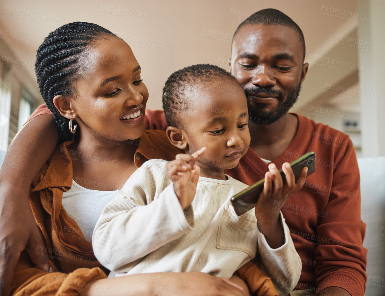 Buy stock photo Happy, bonding and family time with a black family on a video call. Young parents being affectionate with their baby while streaming and watching something on a phone, enjoying time with their son