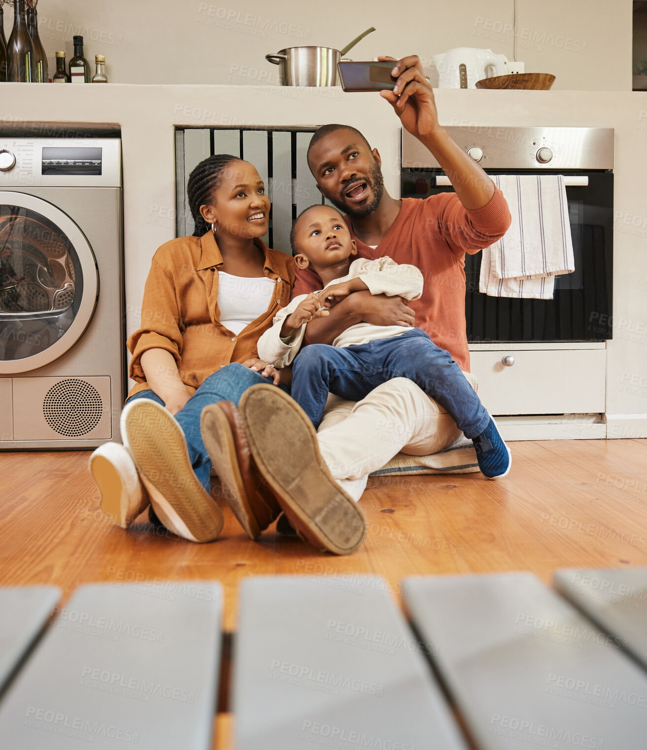 Buy stock photo Fun family taking selfie on phone, bonding or smiling for social media or video call. Adorable, cute or little boy sitting with parents in home kitchen, enjoying family time as mother, father and son