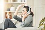 Carefree, smiling and relaxed woman listening to music, singing and having fun while sitting on the couch at home.  Happy, cheerful and content female enjoying radio audio and relaxing on sofa