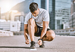 Wellness and fitness runner ties shoes lace before running in a city street during summer. Healthy man athlete prepare sneaker for a comfortable fit for a sport exercise, training or marathon workout
