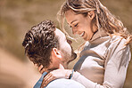 Loving, affectionate and caring young couple bonding while enjoying the day outdoors in nature. Happy, in love and smiling man embracing his wife while holding her outside on a valley or hill.