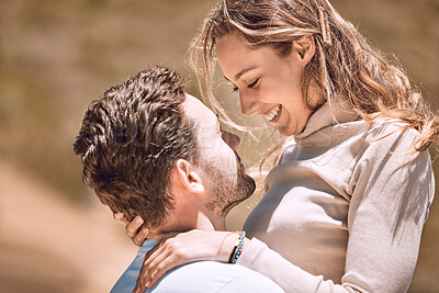 Loving, affectionate and caring young couple bonding while enjoying the day outdoors in nature. Happy, in love and smiling man embracing his wife while holding her outside on a valley or hill.