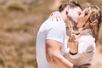 Buy stock photo Young woman showing her engagement ring finger while couple kiss enjoying a sweet moment together. In love, romantic and kissing couple ready for marriage loving romance in the sun and nature 