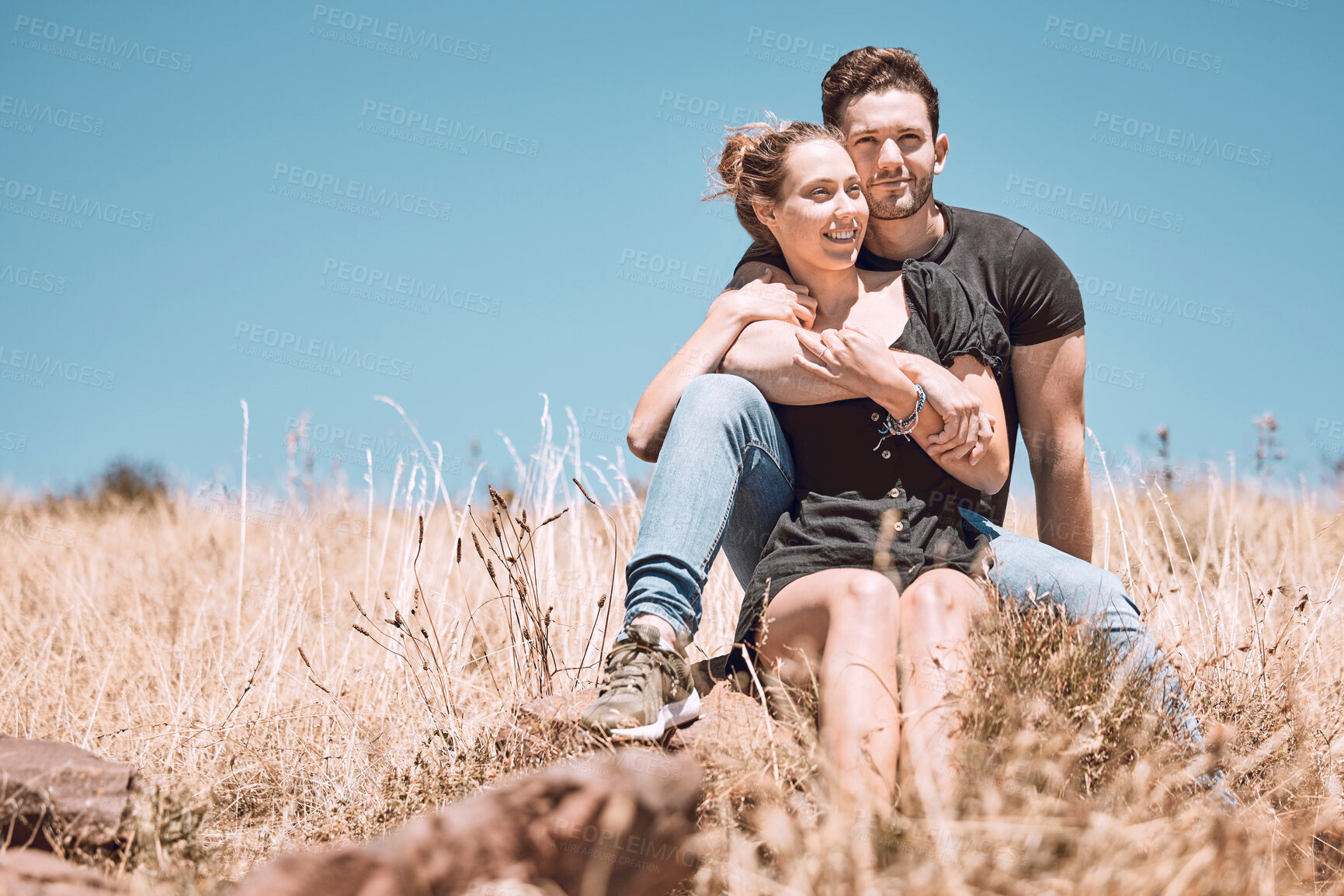 Buy stock photo Carefree, smiling and relaxed couple bonding, having fun and looking at the view while sitting on the grass in a nature park together. Loving, caring and romantic boyfriend and girlfriend hugging