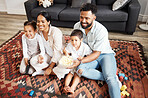 Happy, bonding and family time at home with a smiling family watching a movie and having snacks on a floor. Young parents being affectionate with their children and enjoying time together indoors