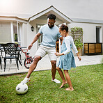 Father and daughter playing soccer in the backyard at home, smiling while bonding and having fun. Happy parent being playful and enjoying family time with his child. Guy being active with his kid