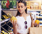 Shopping, holding and looking at fruit at shop, buying healthy food and examining items at a grocery store. Woman deciding, choosing and picking ripe, fresh and delicious produce alone at a market
