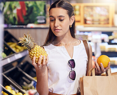 Buy stock photo Shopping, holding and looking at fruit at shop, buying healthy food and examining items at a grocery store. Woman deciding, choosing and picking ripe, fresh and delicious produce alone at a market