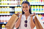 Portrait, shopping bags and woman smiling as she buys groceries at the supermarket. Cheerful, young and shopaholic caucasian woman purchasing in a shopping center and buying food.

 