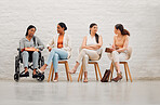 Inclusive group of women sharing idea and goals, planning and talking, sitting together at work. Diverse creative team chatting, brainstorming, discussing an idea for a startup or marketing strategy