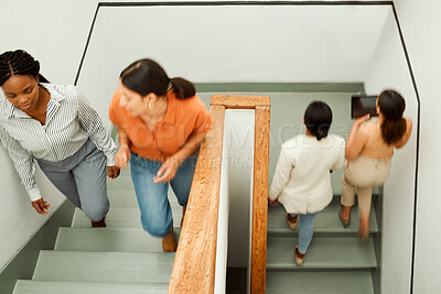 Buy stock photo Overhead of busy, diverse female colleagues returning to work after break, with blurred digital tablet screen. Active business woman in motion talking and walking up office building stairs.