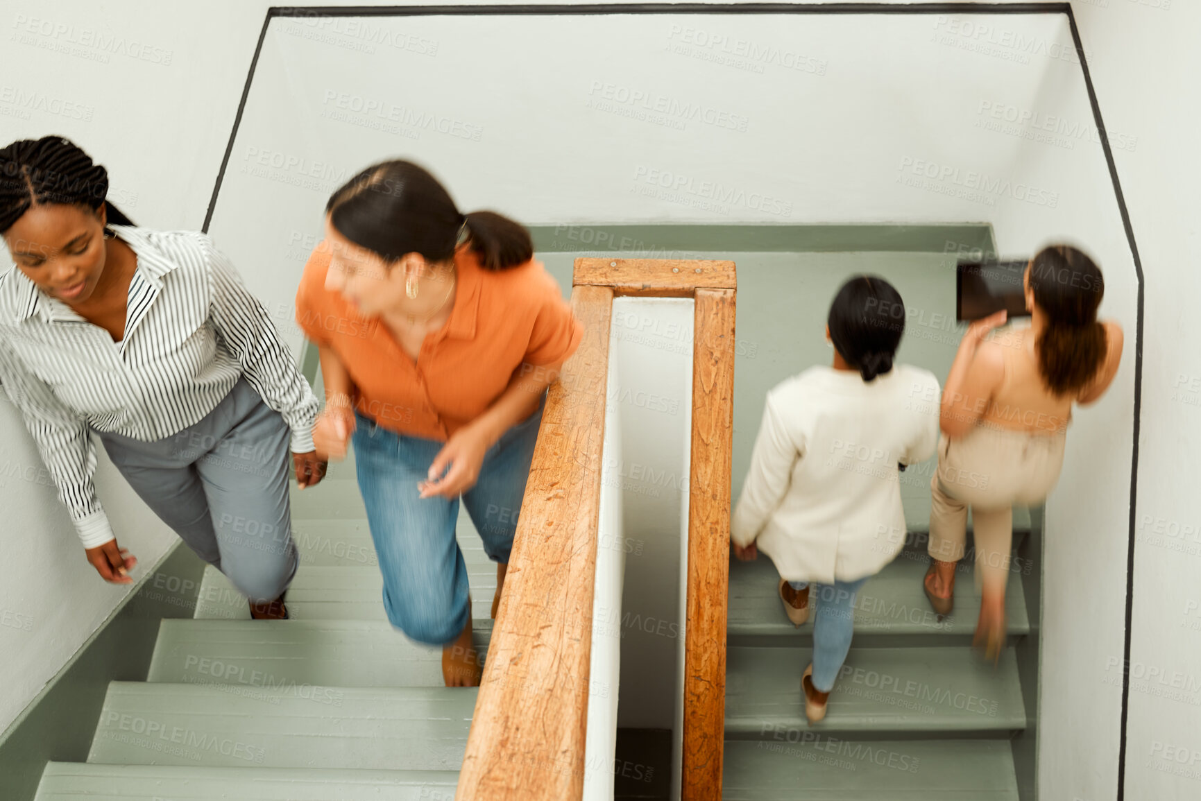 Buy stock photo Overhead of busy, diverse female colleagues returning to work after break, with blurred digital tablet screen. Active business woman in motion talking and walking up office building stairs.