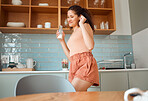 Happy, cheerful and excited woman dancing, playful and enjoying leisure morning in the kitchen while drinking milk. Latin woman having fun, celebrating and joyful in the morning at home