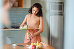 Healthy, nutrition and wellness lifestyle young woman making fresh, green detox fruit smoothie for her vegan diet at home in her kitchen. Vegetarian female drinking her organic homemade juice 