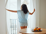 Awake, waking up and fresh new day or morning for a young woman opening the curtains. Backview of a carefree female with hope thinking while looking out the window in her house or at home
