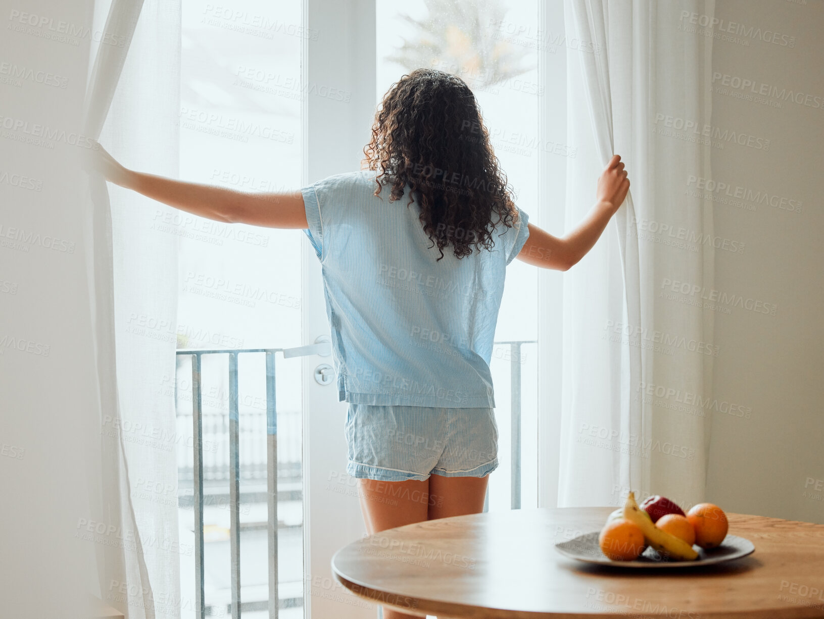 Buy stock photo Awake, waking up and fresh new day or morning for a young woman opening the curtains. Back view of a carefree female with hope thinking while looking out the window in her house or at home