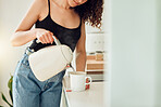 Young woman making a cup of organic green tea before starting her morning at home. Female trying a health cleanse, beginning a slimming detox or diet with a healthy drink for breakfast