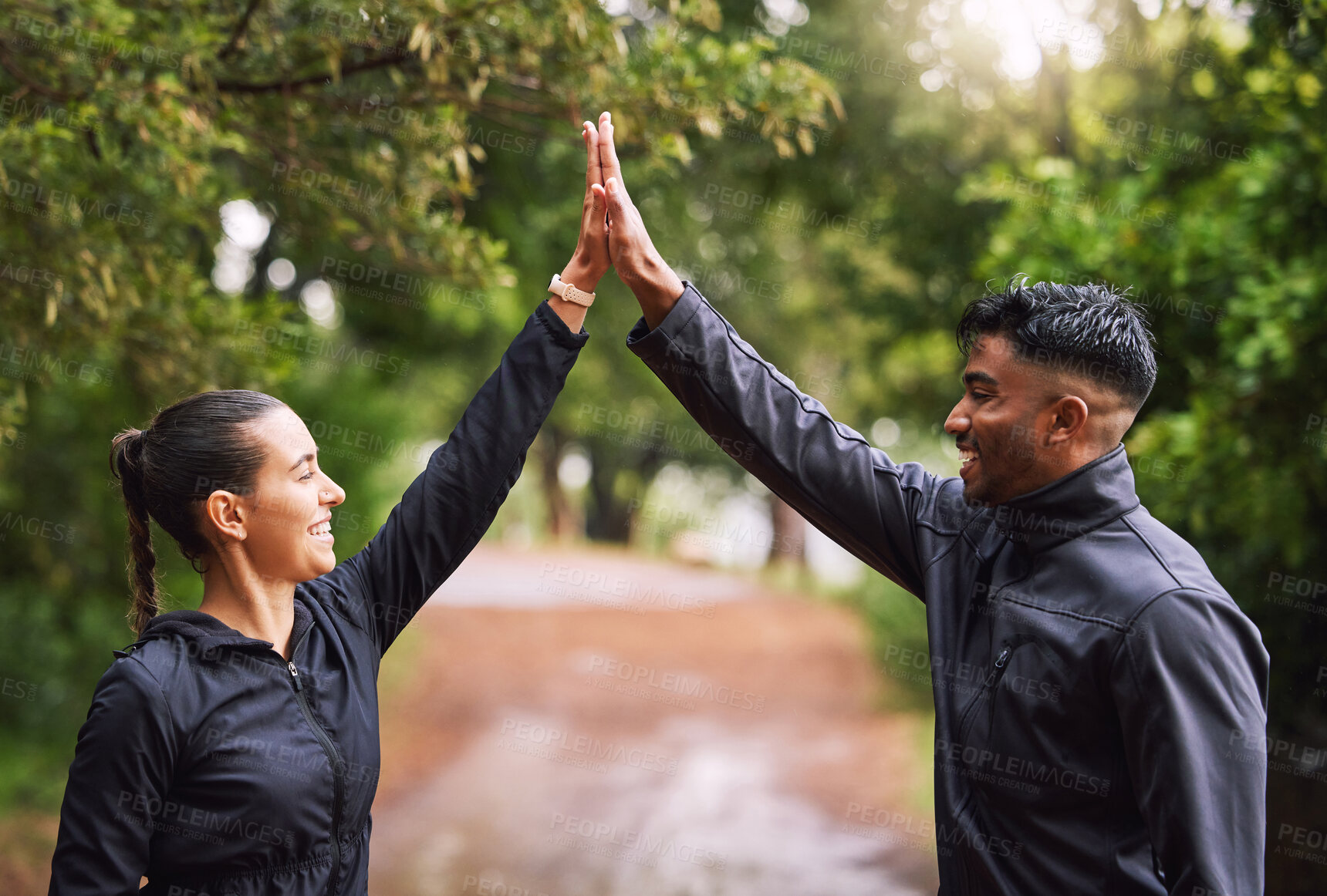 Buy stock photo Athletic couple high five while exercising in a park or forest, celebrating and winning before a run. Fit boyfriend and girlfriend bonding while keeping fit and healthy. Fun lovers being active 