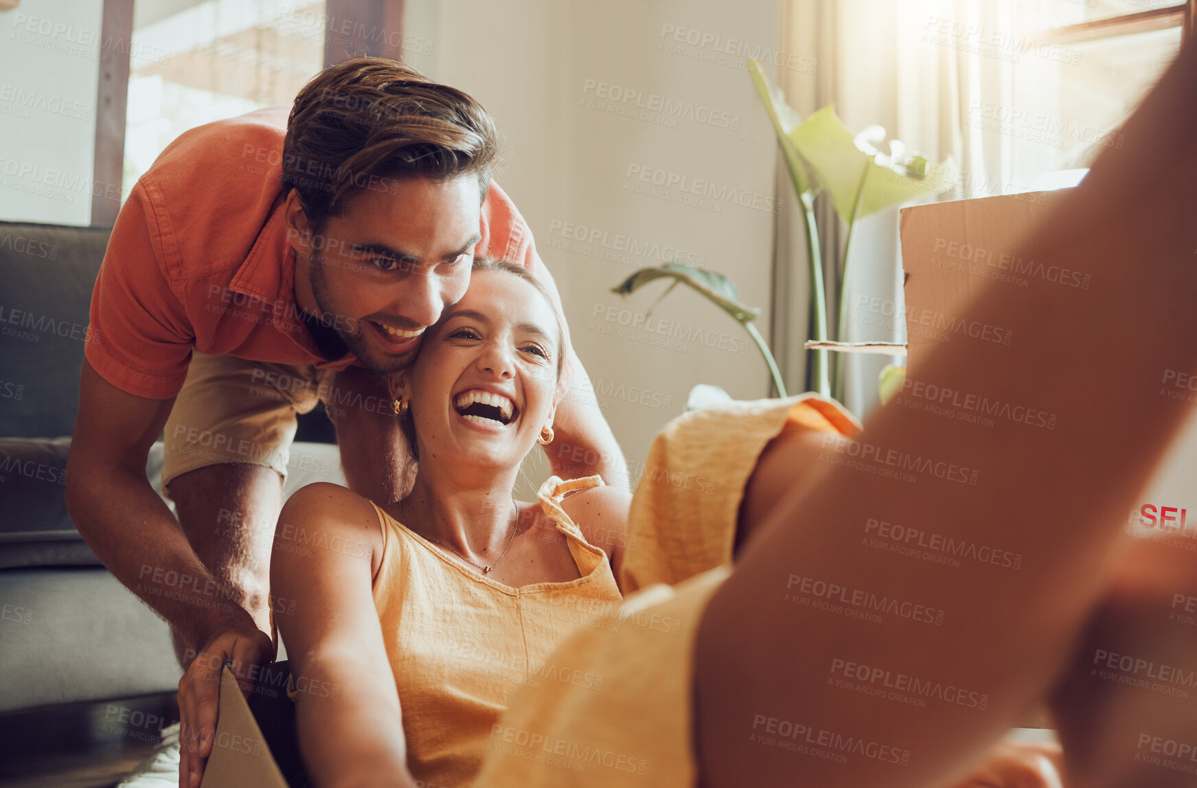 Buy stock photo Fun couple moving into first house together, having fun and enjoying their freedom. Young newlyweds enjoying new home, fooling around and feeling excited. Cheerful homeowners playing while unpacking
