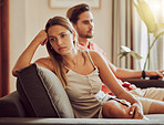 Unhappy, sad and annoyed couple after a fight and are angry at each other while sitting on a couch at home. A woman is stressed, upset and frustrated by her boyfriend after an argument