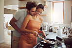 Happy, loving and cooking couple bonding and having fun while spending time together at home. Playful, fun and smilinghusband and wife hugging while preparing a meal and sharing a romantic moment