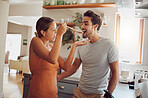Fun, food and young couple cooking in a kitchen at home, bonding while being playful and looking happy. Husband and wife being affectionate and flirting, preparing food and fooling around together