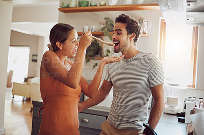 Buy stock photo Fun, food and young couple cooking in a kitchen at home, bonding while being playful and looking happy. Husband and wife tasting and flirting, preparing food and fooling around together