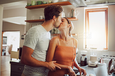 Buy stock photo Romantic couple kissing, cooking and showing affection in love while bonding together in a kitchen at home. Caring boyfriend and girlfriend in a loving relationship sharing an intimate special moment