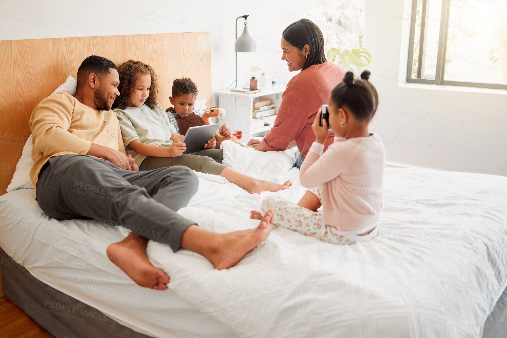 Buy stock photo Happy family in the bedroom as the mother and father play, smile and relax with their children. Brother and sisters sitting together with their mom and dad. Latino siblings resting with parents
