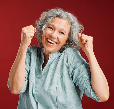 Celebrating, cheering and winning with a happy, smiling and excited senior female posing in studio against a red background. Portrait of a cheerful, wow and positive mature female with a fist gesture