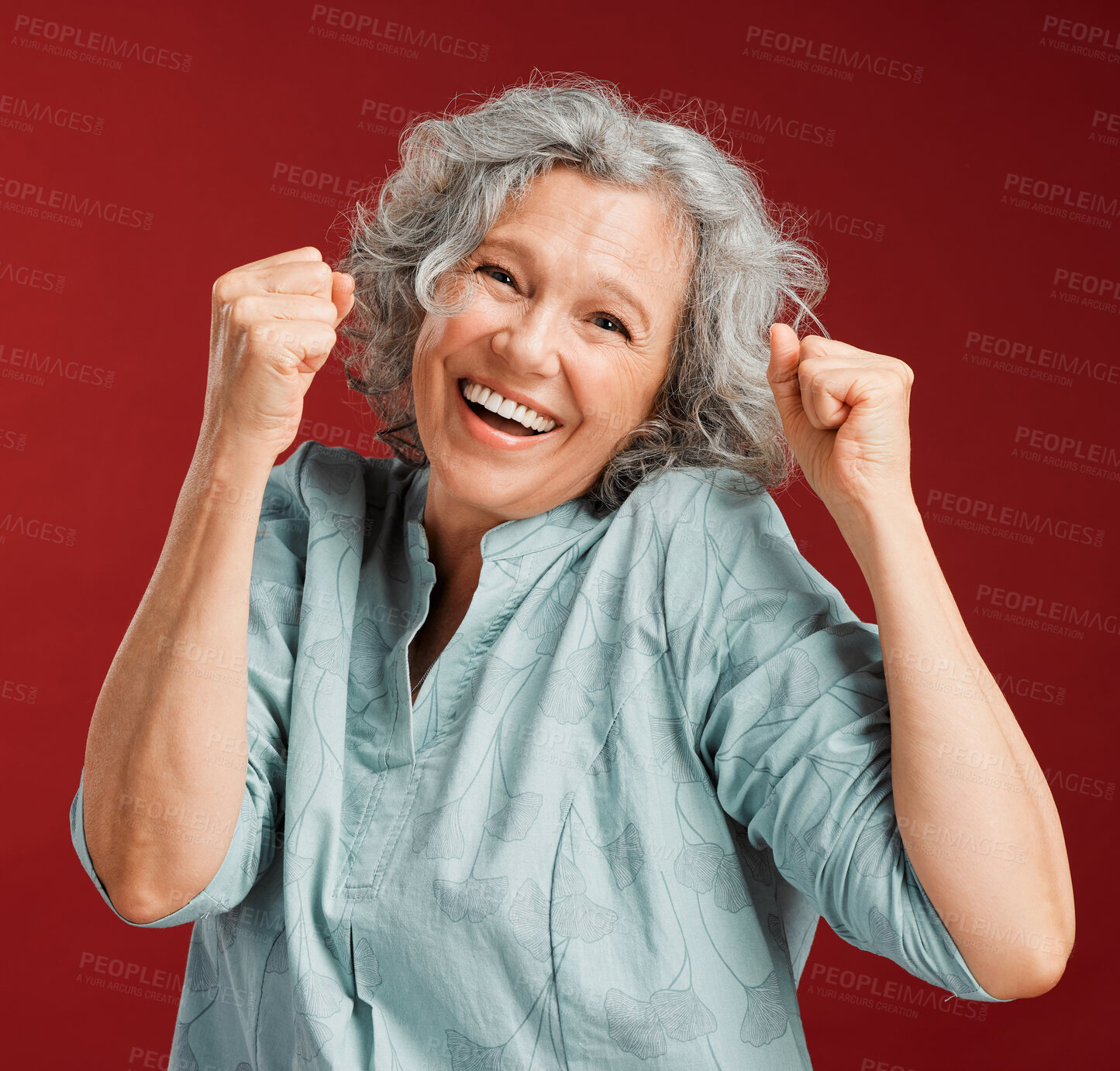 Buy stock photo Celebrating, cheering and winning with a happy, smiling and excited senior female posing in studio against a red background. Portrait of a cheerful, wow and positive mature female with a fist gesture
