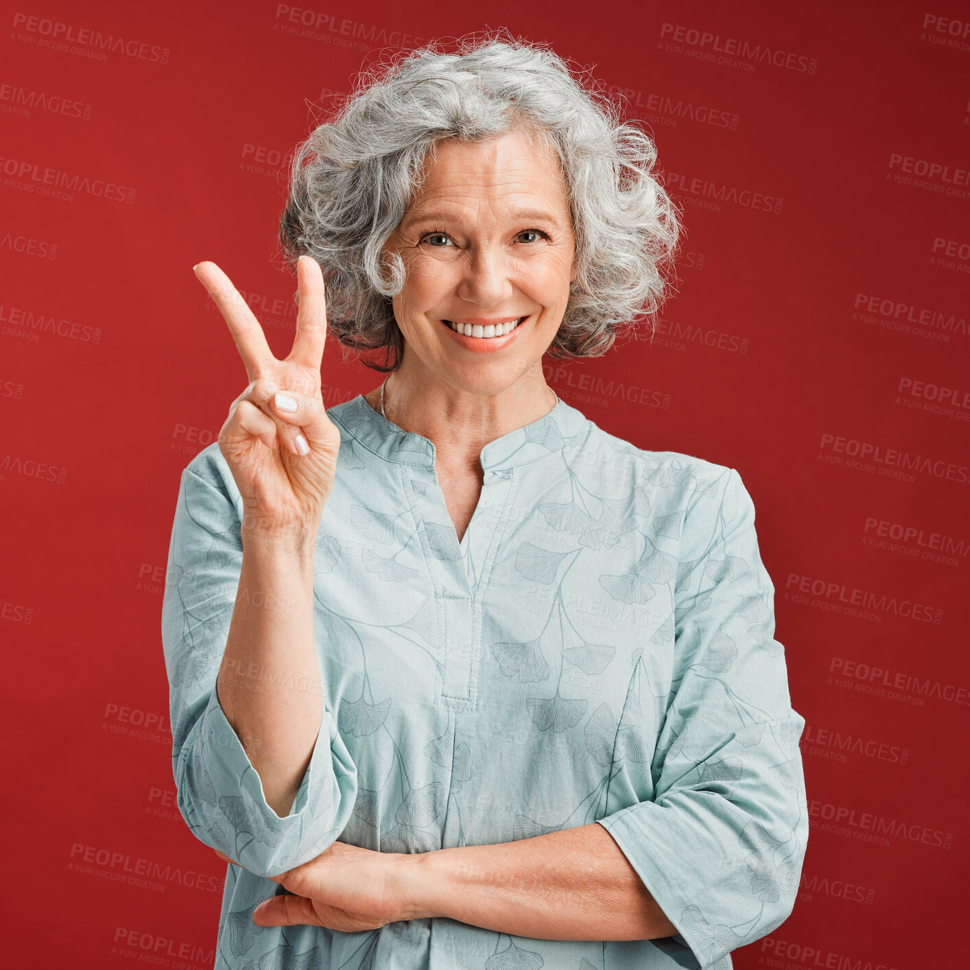 Buy stock photo Senior woman express peace sign, v gesture and emoji with fingers on red studio background. Portrait of carefree, cool and smiling lady in positive, playful and fun mood showing victory with hand