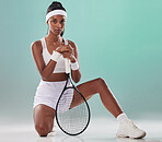 Tennis, sports and training with a woman player posing with a racket in studio against a green background. Portrait of a young, active and healthy athlete looking serious and ready to compete