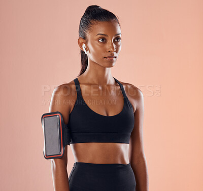 Buy stock photo Healthy, fit and active female fitness model listening to music on wireless earpods or earphones in a studio against a peach background. Workout and exercise with a sporty young athlete