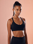 Fit, slim and serious woman feeling confident about her body and health while standing against a pink studio background. Portrait of a sporty and determined woman ready to exercise to stay in shape