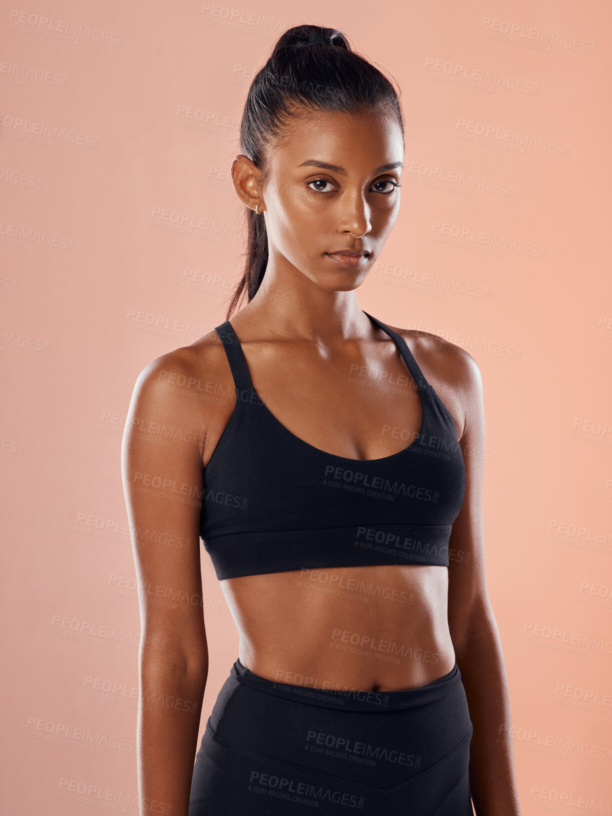 Buy stock photo Fit, slim and serious woman feeling confident about her body and health while standing against a pink studio background. Portrait of a sporty and determined woman ready to exercise to stay in shape