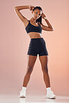 Beautiful, young and active fitness woman in sportswear with her arms up while tying her hair. Athletic female getting ready to workout at gym. Full length of attractive lady with healthy lifestyle.