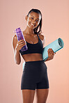 Fit, healthy and athletic woman in studio holding mat and water bottle for yoga, pilates or exercise on pink background. Portrait of sporty, active or slim athlete preparing for workout and training 