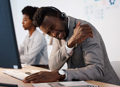 Buy stock photo Pain, injury and hurt call center agent holding his shoulder in agony while working in the office. Young African American male customer service consultant suffering from a painful arm