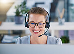 Call center agent helping clients online while talking on a headset in a modern office, enjoying her career. Customer service and support with a happy, friendly woman excited to guide and answer 