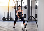 Fitness, exercise and battle ropes with a young woman athlete in a routine workout, exercising or training in a gym. Health, wellness and active lifestyle with an athletic, sporty and young female 