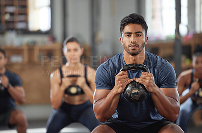 Buy stock photo Personal trainer squatting with a team of athletes in a workout session at a fitness club. Portrait of a fit, active and serious young male coach using a kettlebell and training a group of people