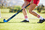 Field hockey, sports and training with a player hitting a ball with a stick and practicing for a match or sport event. Closeup of a sporty athlete being active, healthy and fit while running outside