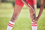 Medical knee injury, football or sport player in pain with sore or hurt muscle touching leg on a sports field. Low angle of young soccer athlete with broken bone or injured joint during training